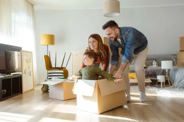 Happy family with one child having fun in their new home surrounded by boxes